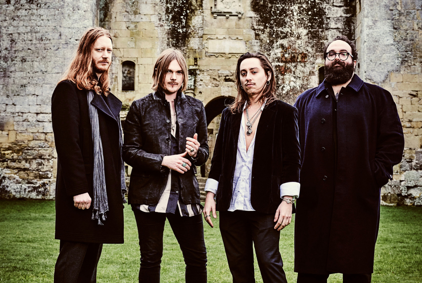 4 members of the band Mirador standing outside in front of an old building.